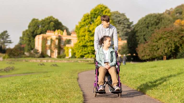 Visitor in a wheelchair with man pushing with Killerton House in the background